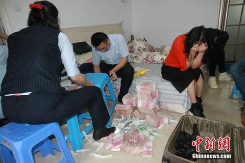 圖為南寧市良慶區五象大道某小區的清查現場狀況。警力在嫌疑人房內現場繳獲大量現金。銀行工作人員（左）正在清驗。